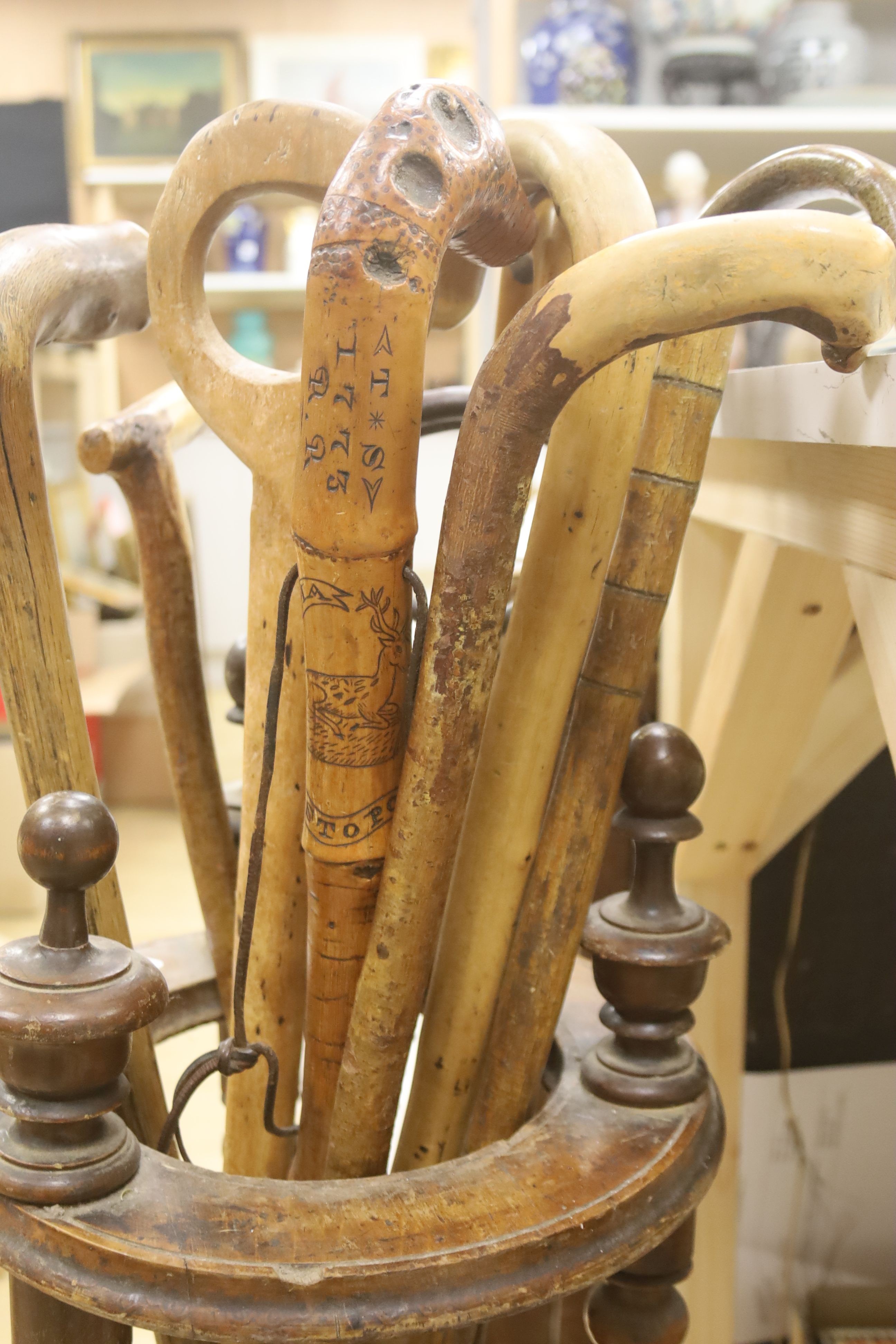 A circular turned beech stick stand, containing various walking sticks and a shooting stick